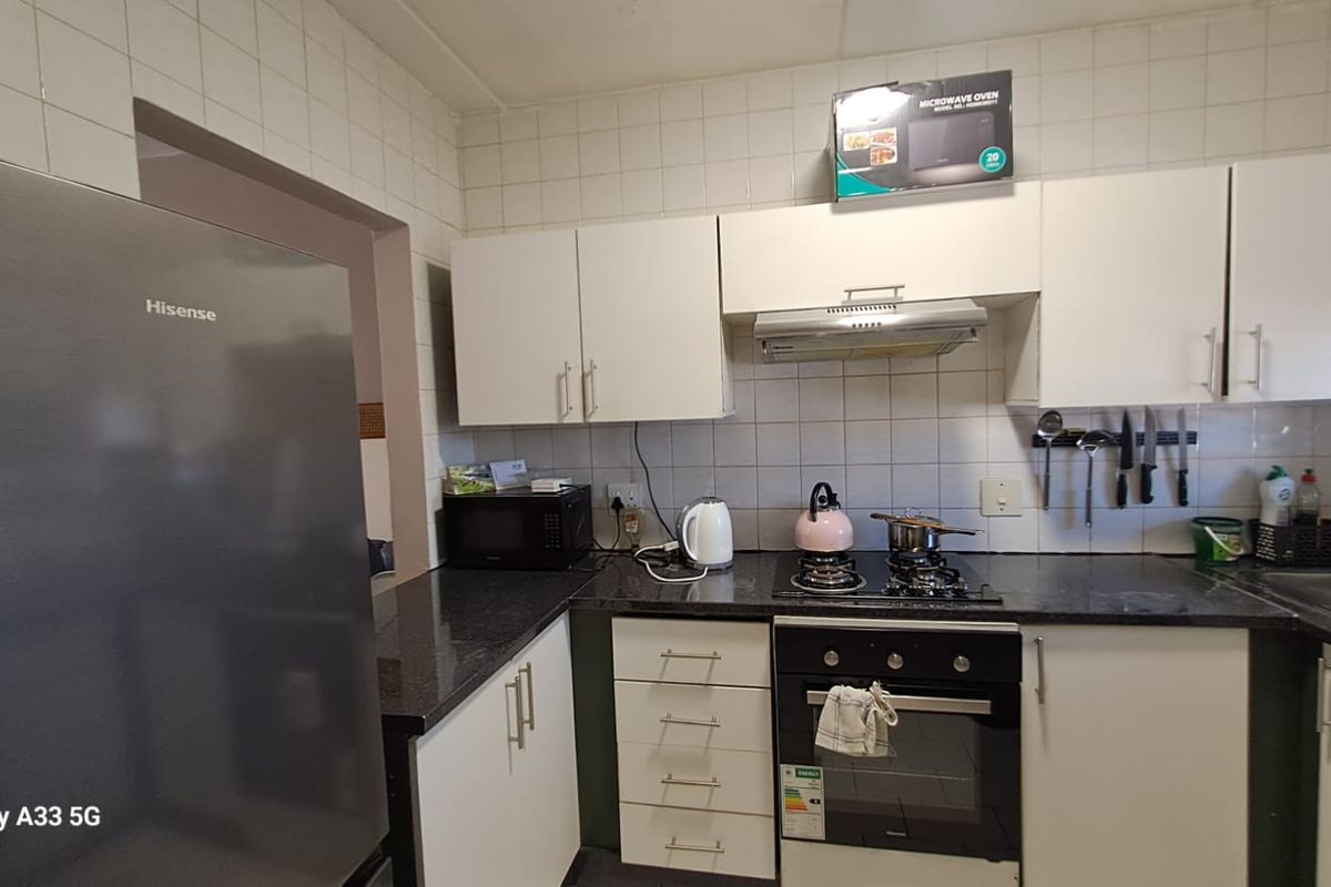 A functional kitchen featuring white cabinetry, dark granite countertops, a built-in oven, gas hob, and an extractor fan.