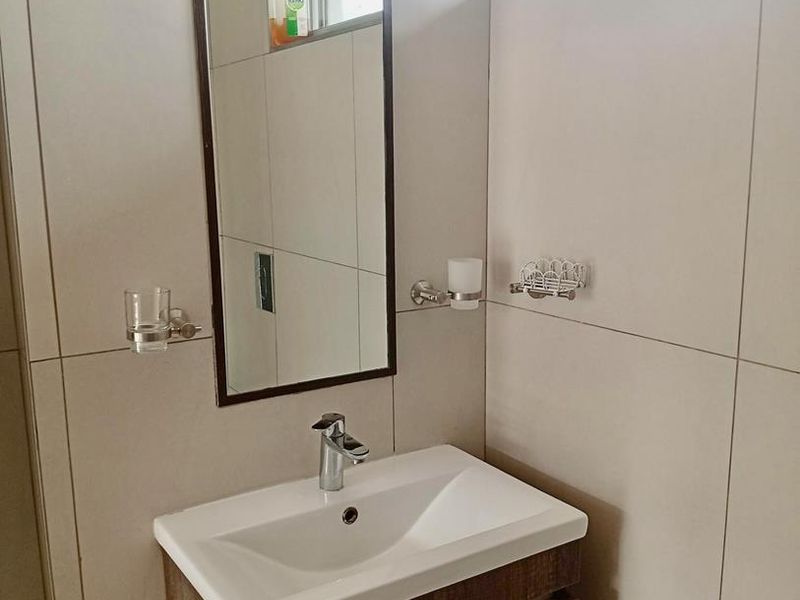 A modern bathroom featuring a wall-mounted vanity with a ceramic basin, chrome mixer tap, and neutral wall tiling.
