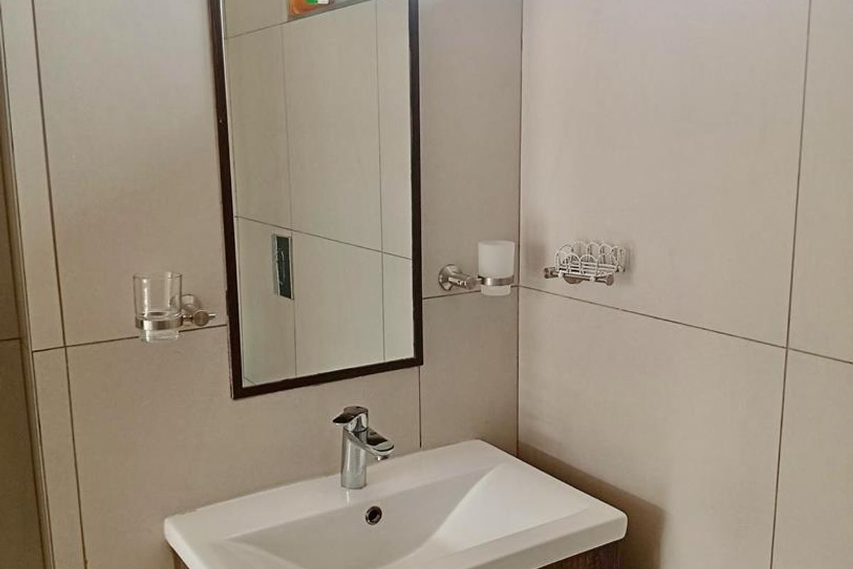 A modern bathroom featuring a wall-mounted vanity with a ceramic basin, chrome mixer tap, and neutral wall tiling.