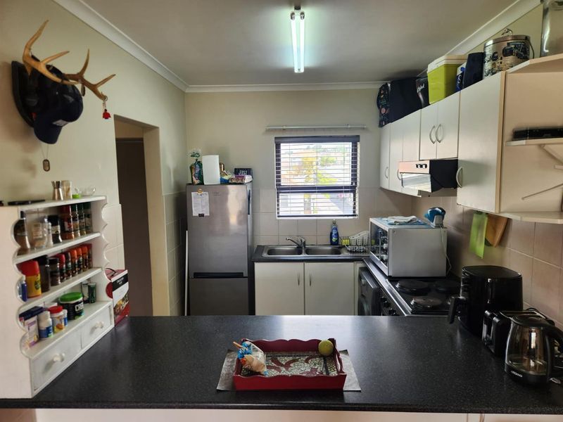 Functional kitchen featuring built-in cabinetry, a double bowl sink, tiled backsplash, and a breakfast bar, providing a practical layout for daily meal preparation.