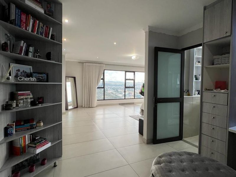 Spacious bedroom featuring modern tiled flooring, built-in cabinetry, and large windows offering expansive views, with an adjoining en-suite bathroom.