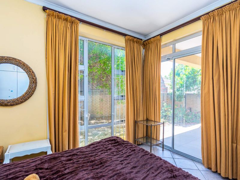 Bedroom featuring tiled flooring and large aluminium sliding doors providing direct access to the outdoor patio area.