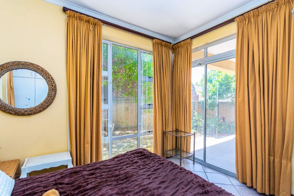 Bedroom featuring tiled flooring and large aluminium sliding doors providing direct access to the outdoor patio area.