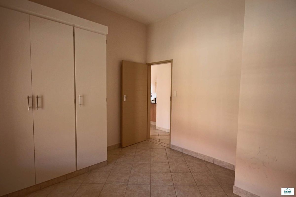 A bedroom featuring built-in white cabinetry, tiled flooring, and a doorway leading to an adjacent living space.