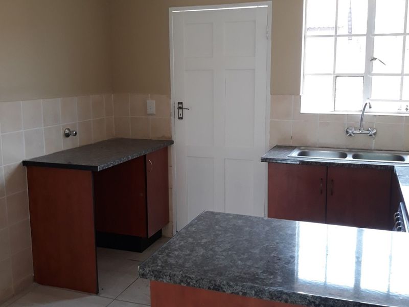 A functional, empty kitchen featuring laminate countertops, double bowl sink, tiled splashbacks, and built-in cabinetry, offering a blank canvas for renovation.