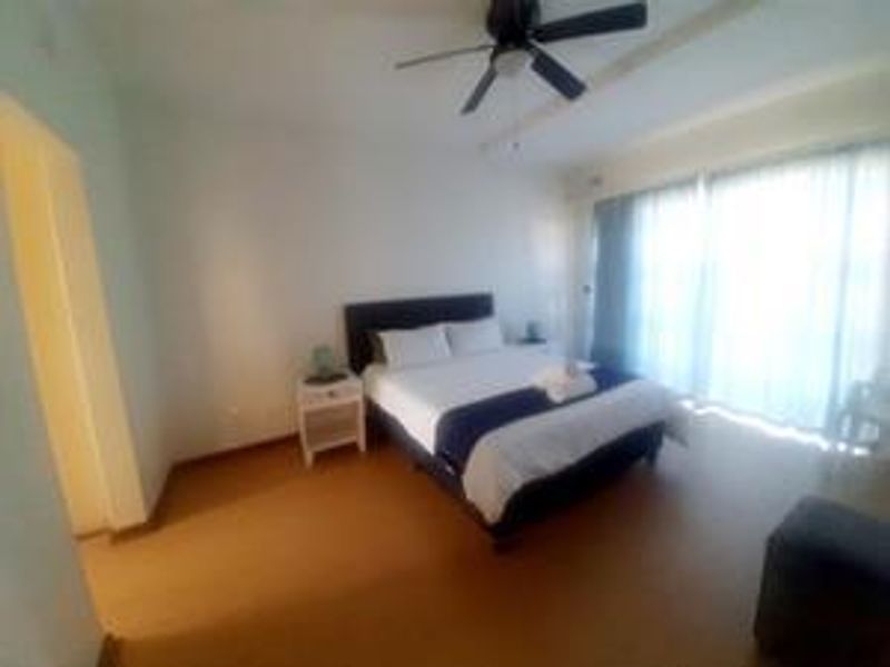 A spacious bedroom featuring a ceiling fan and large sliding glass doors that provide ample natural light.