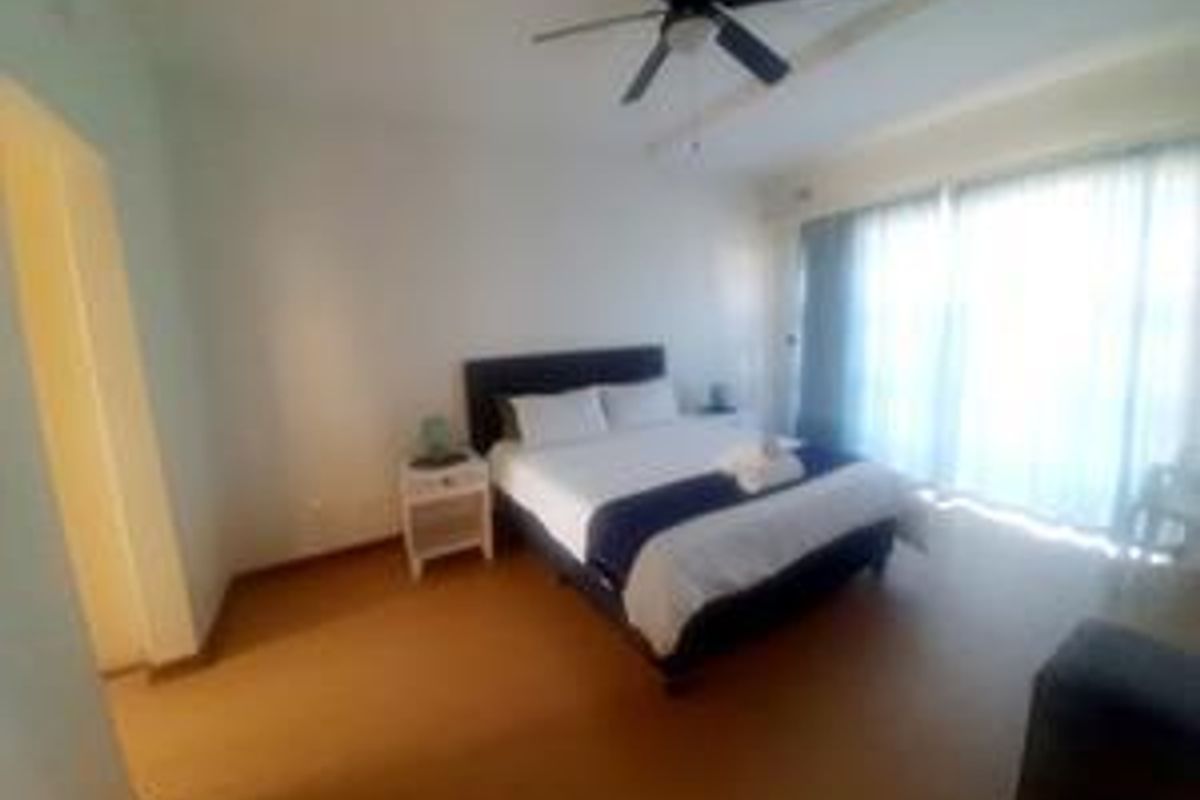 A spacious bedroom featuring a ceiling fan and large sliding glass doors that provide ample natural light.