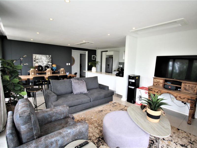 Spacious open-plan living and dining area featuring modern recessed lighting, ducted air conditioning, and a functional kitchen island with tiled flooring throughout.