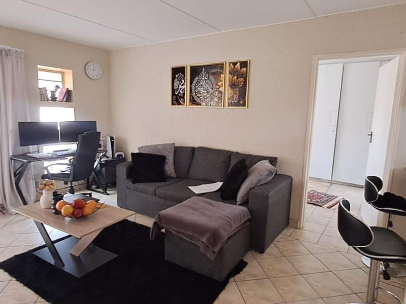 A living room area featuring tiled flooring and access to an adjacent room with built-in storage.