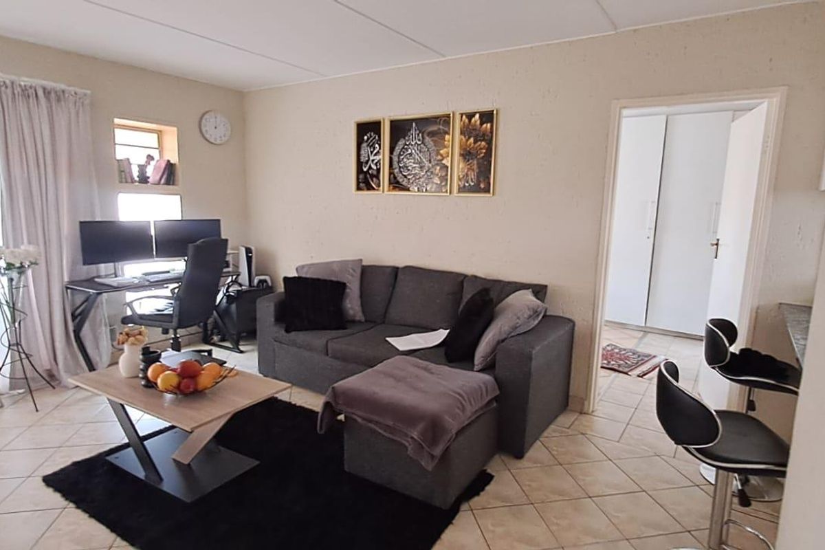 A living room area featuring tiled flooring and access to an adjacent room with built-in storage.