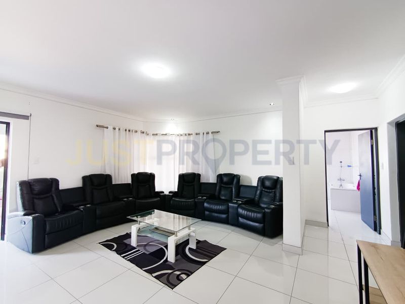 Spacious living room featuring neutral tiled flooring, coved cornicing, and recessed ceiling lighting, providing a bright and open area for relaxation.