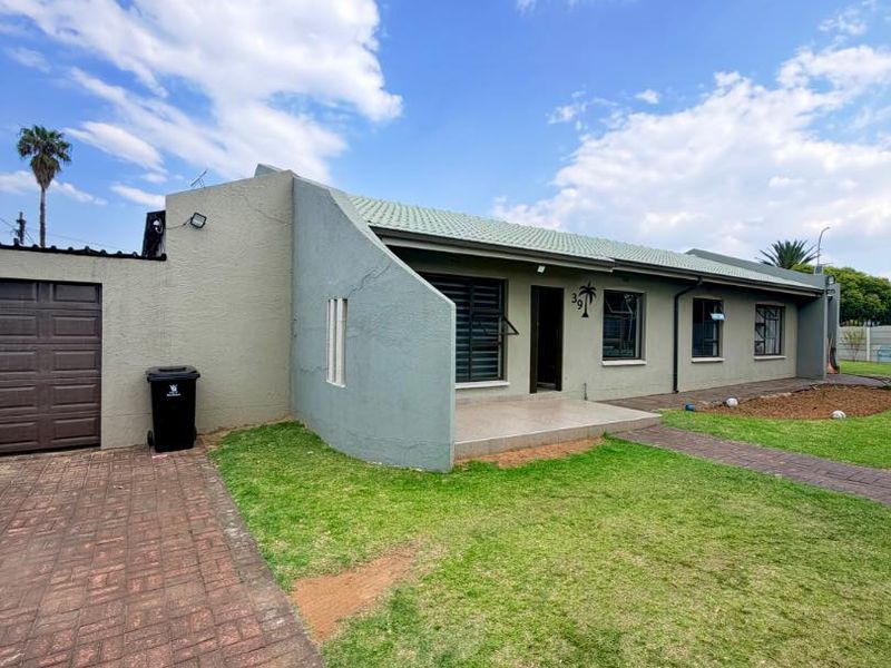 Front view of a single-story house featuring a paved driveway, tiled entrance porch, and a secure garage, set on a manageable lawn.
