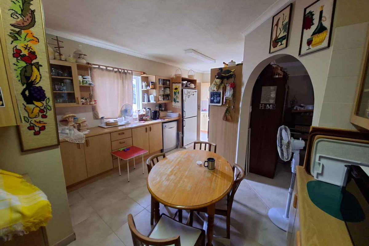 A functional kitchen featuring light wood cabinetry, tiled flooring, and an arched doorway leading to an adjacent living space.