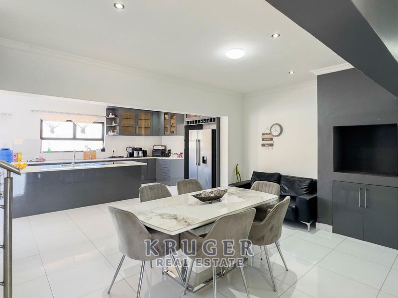 Spacious open-plan living and dining area featuring a modern kitchen with a central island, sleek cabinetry, and polished tiled flooring throughout.