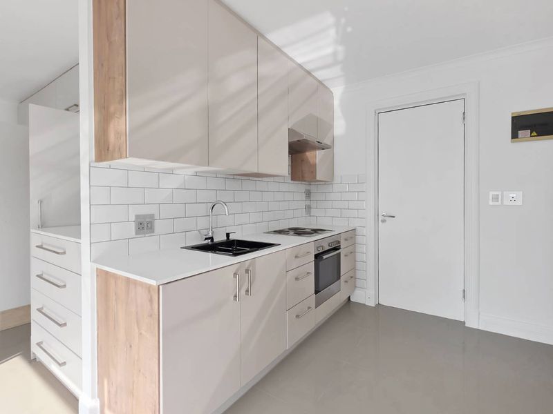 Modern kitchen featuring sleek cabinetry, subway tile backsplash, integrated oven, electric cooktop, and a contemporary sink, presented in a clean, minimalist style.
