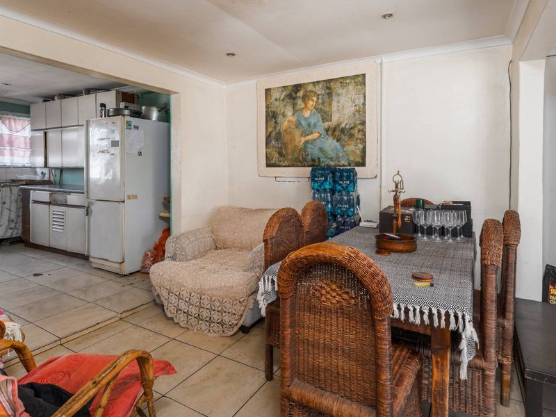 Open-plan living and dining area flowing into a functional kitchen with tiled flooring and recessed lighting.