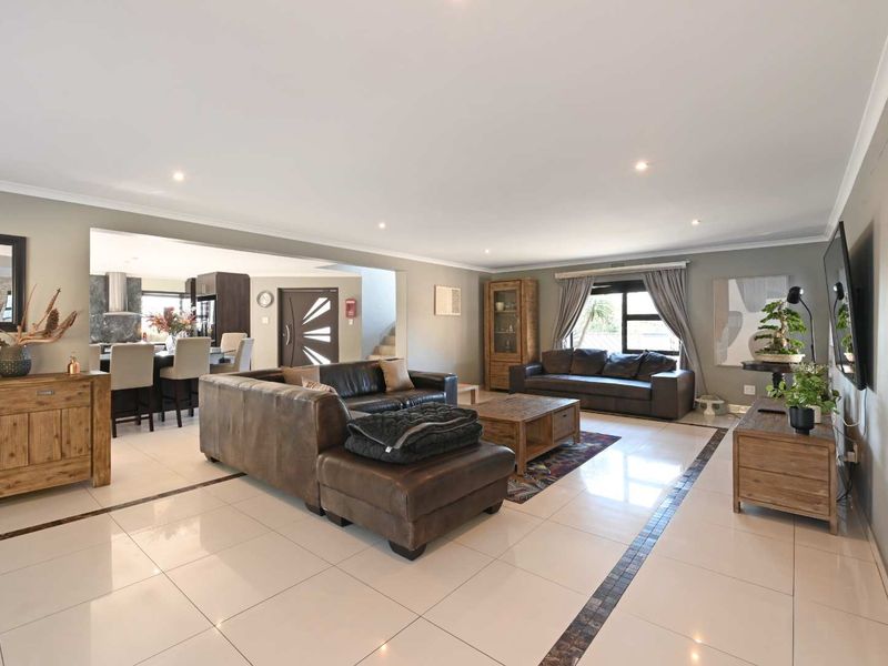 Spacious open-plan living area featuring polished tiled floors with decorative borders, recessed downlighting, and seamless flow into the adjacent kitchen space.