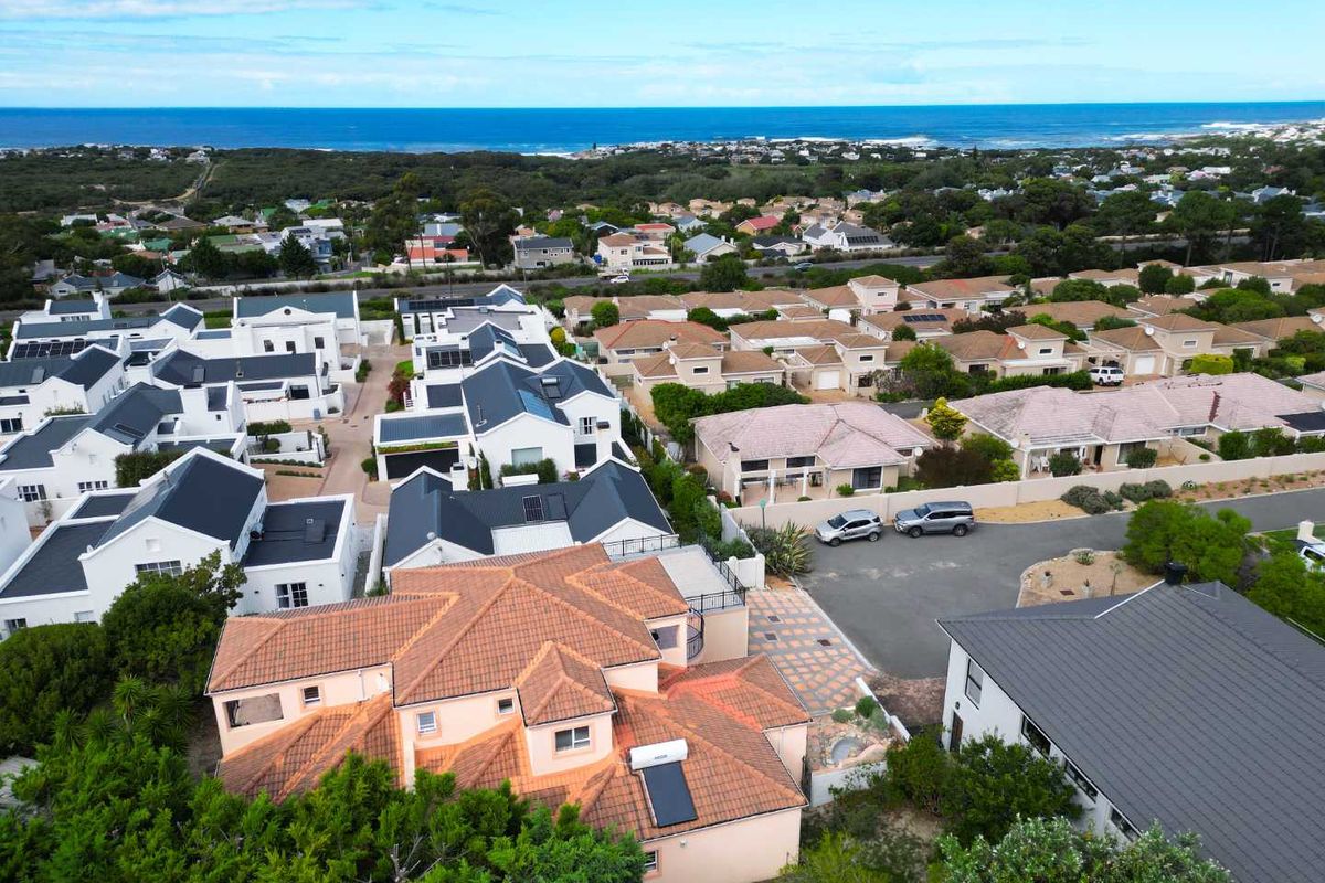 Aerial view of the residential property showing the roof structure, solar water heating system, and surrounding coastal neighborhood landscape.