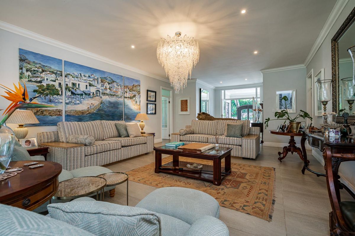 Spacious living room featuring tiled flooring, crown molding, and a prominent decorative chandelier, offering a bright and well-maintained living space.