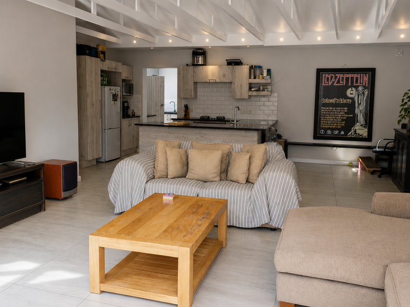 Open-plan living area featuring a modern kitchen with subway tile backsplash, exposed ceiling beams, and tiled flooring throughout.