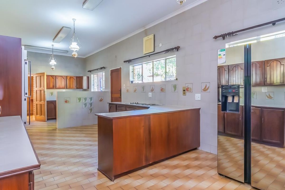 Spacious kitchen featuring wooden cabinetry, tiled flooring, and a functional layout with a central breakfast counter and ample storage space.
