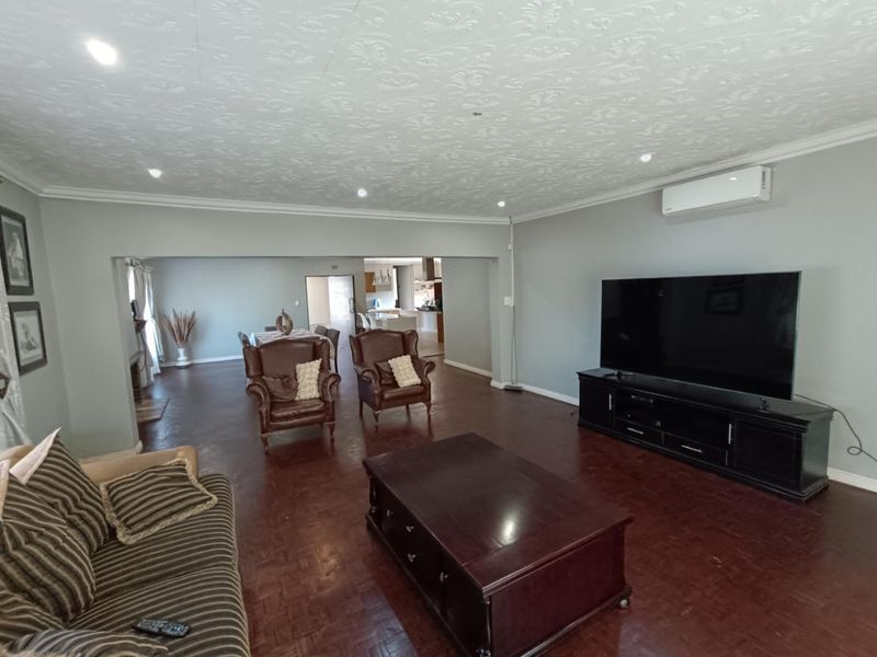 Spacious open-plan living area featuring parquet flooring, a textured ceiling with recessed lighting, and a wall-mounted air conditioning unit.