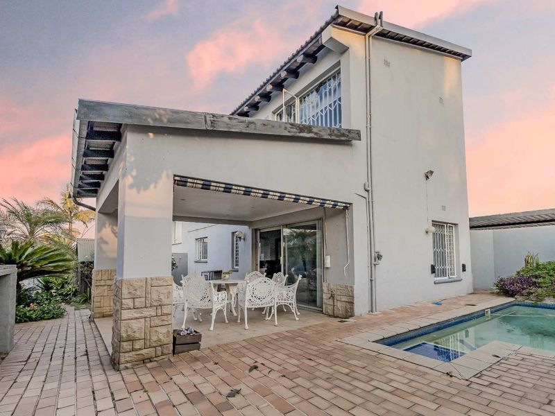 Rear exterior view of the townhouse featuring a covered patio, paved entertainment area, and a private swimming pool.