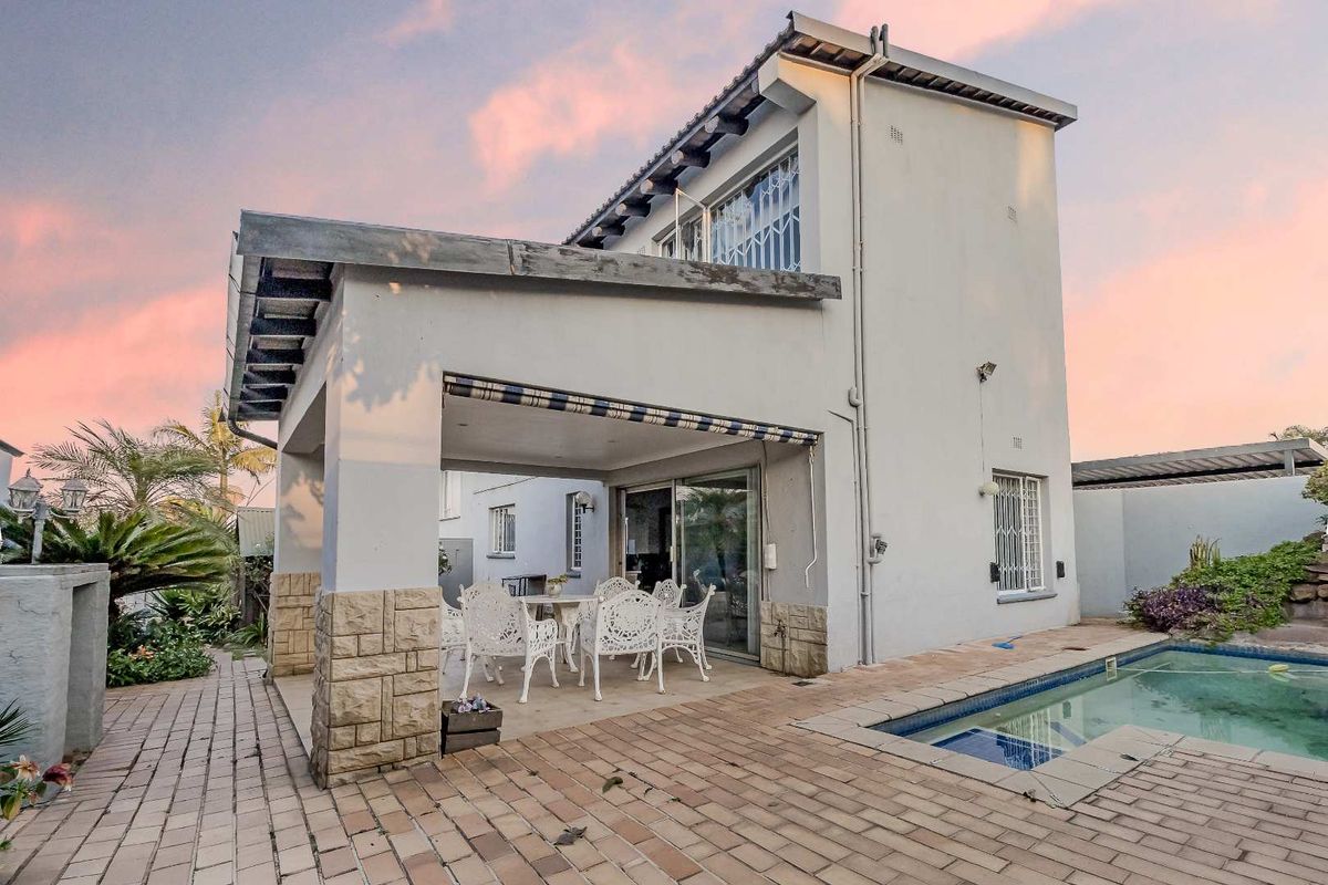 Rear exterior view of the townhouse featuring a covered patio, paved entertainment area, and a private swimming pool.