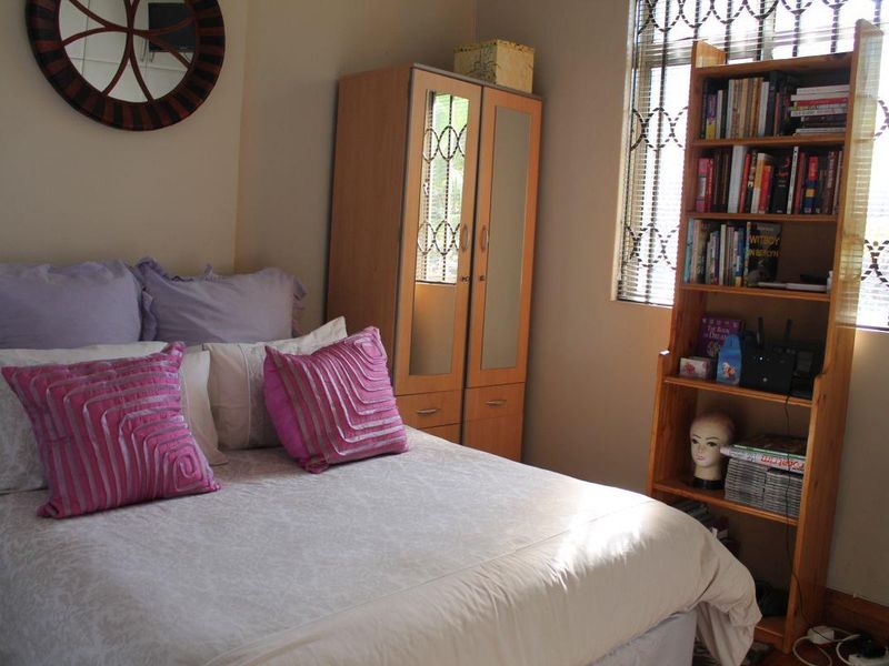 A functional bedroom featuring a built-in wardrobe and security bars on the window, providing a practical and secure living space.
