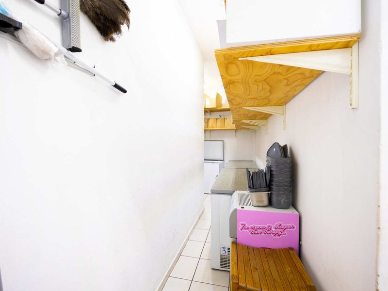 A functional scullery or utility prep area featuring tiled flooring, built-in wooden shelving, and a practical countertop workspace.