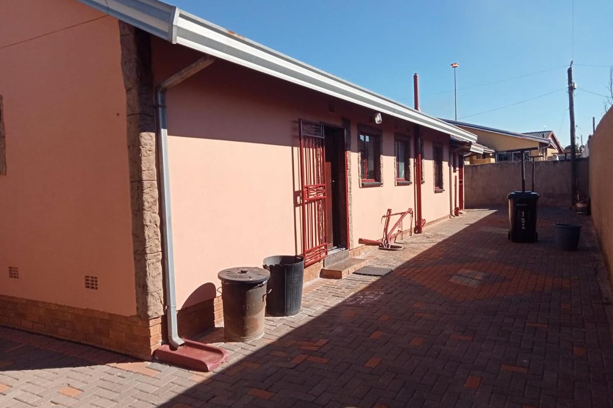 A side view of the house featuring brick paving, exterior wall finishes, and functional guttering systems.