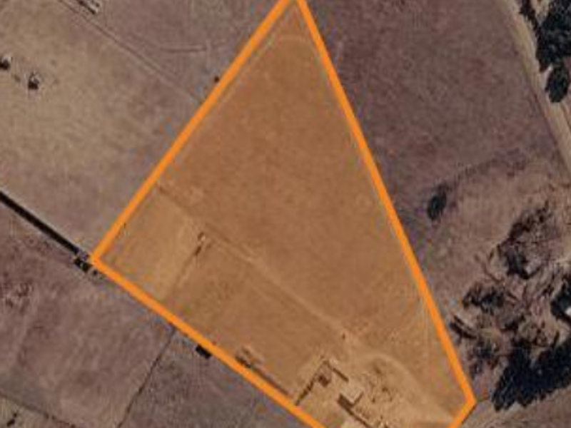 An aerial view of a vacant agricultural land plot with defined boundaries, suitable for development or farming purposes.