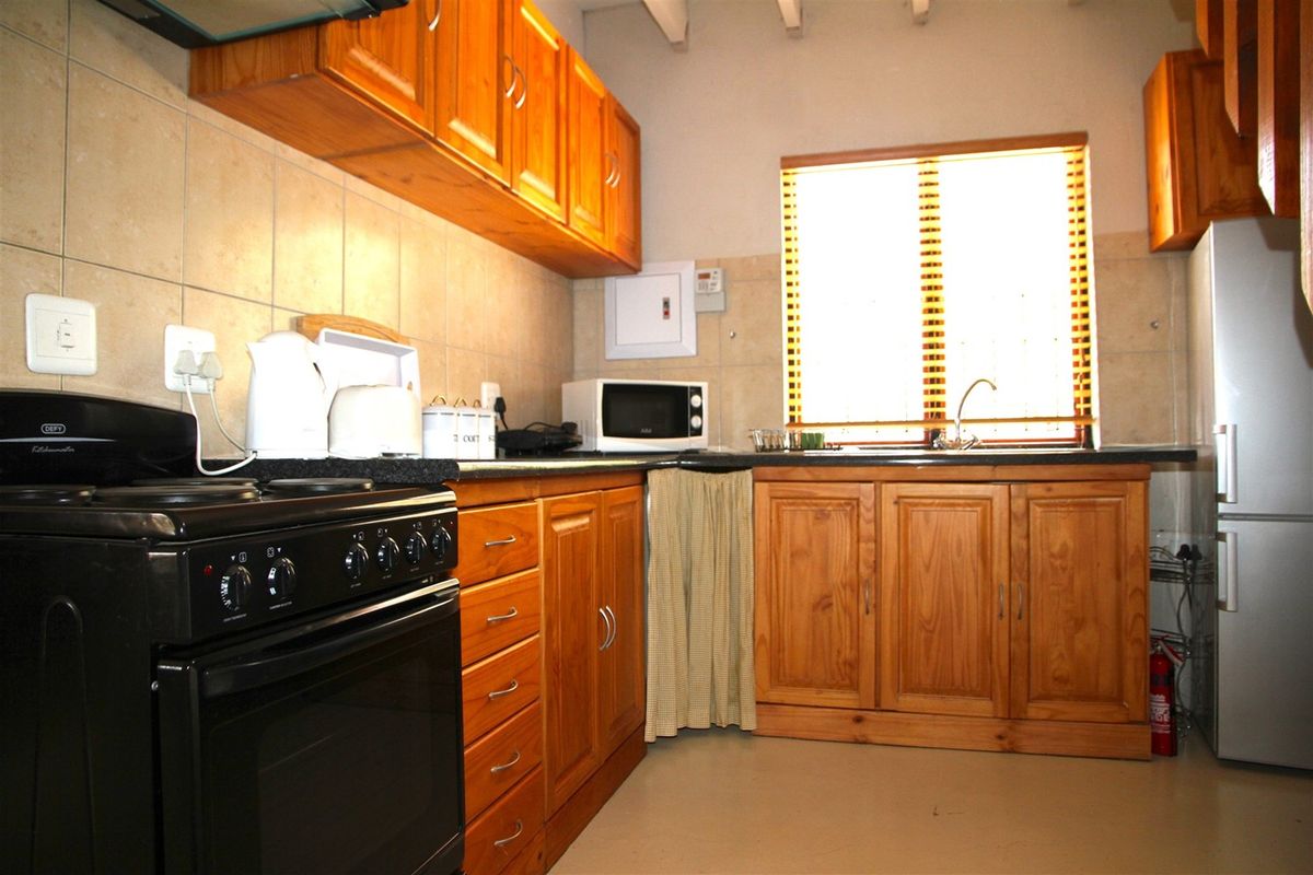 Functional kitchen featuring warm wooden cabinetry, granite countertops, tiled backsplash, and exposed ceiling beams, providing a classic and practical cooking space.
