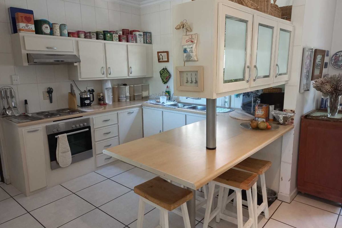 A functional kitchen featuring white cabinetry, a built-in oven with extractor fan, tiled flooring, and a breakfast bar peninsula.