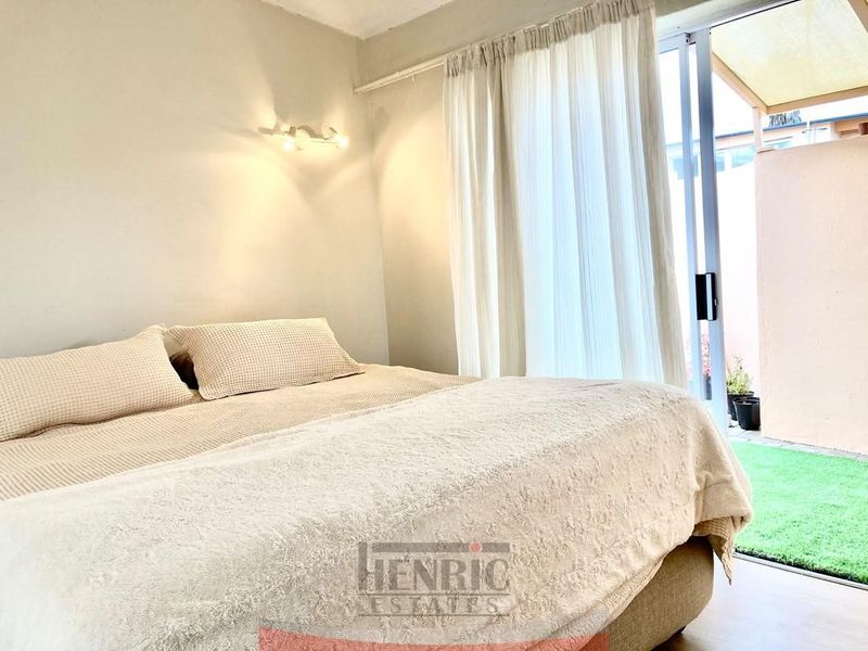 A bright bedroom featuring a sliding glass door that provides direct access to a private outdoor patio area.