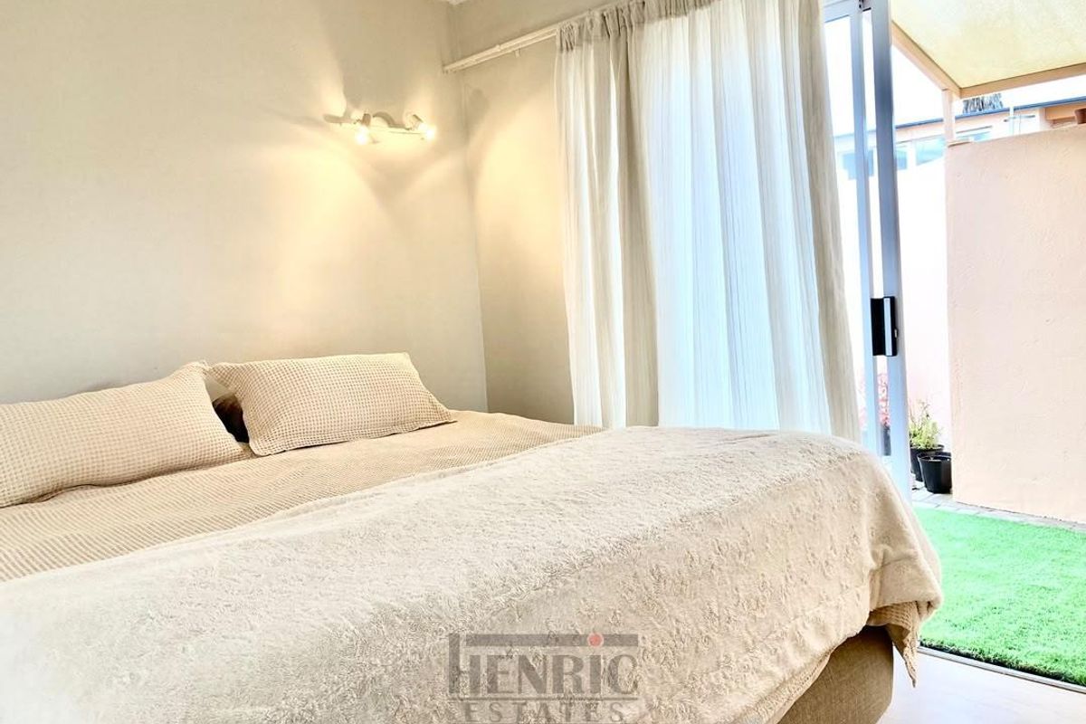 A bright bedroom featuring a sliding glass door that provides direct access to a private outdoor patio area.