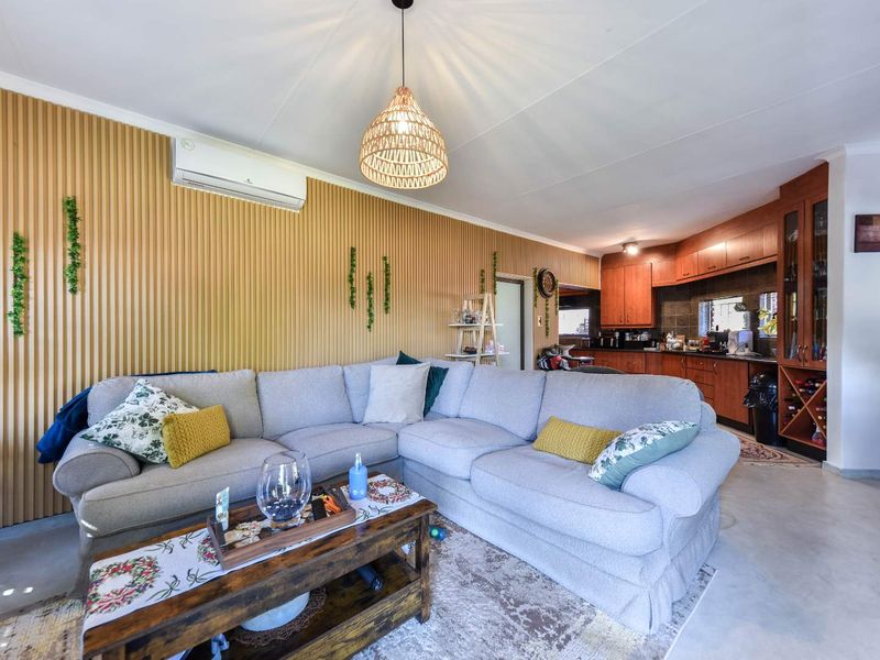 Open-plan living area featuring timber slat wall paneling, split-system air conditioning, and an adjoining kitchen with built-in cabinetry and wine storage.