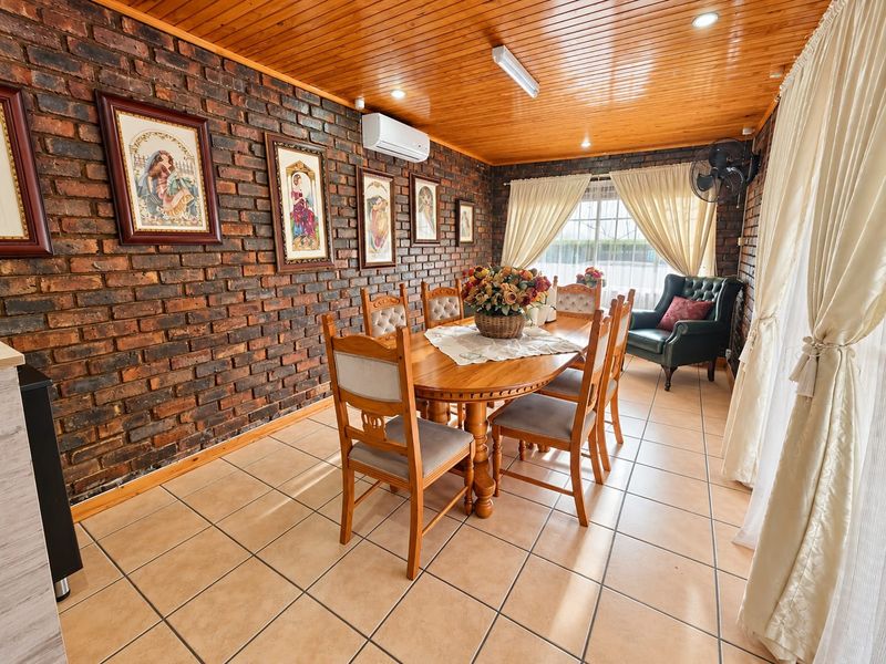 Dining room featuring an exposed brick feature wall, timber ceiling, and ceramic tiled flooring, creating a warm and rustic atmosphere.
