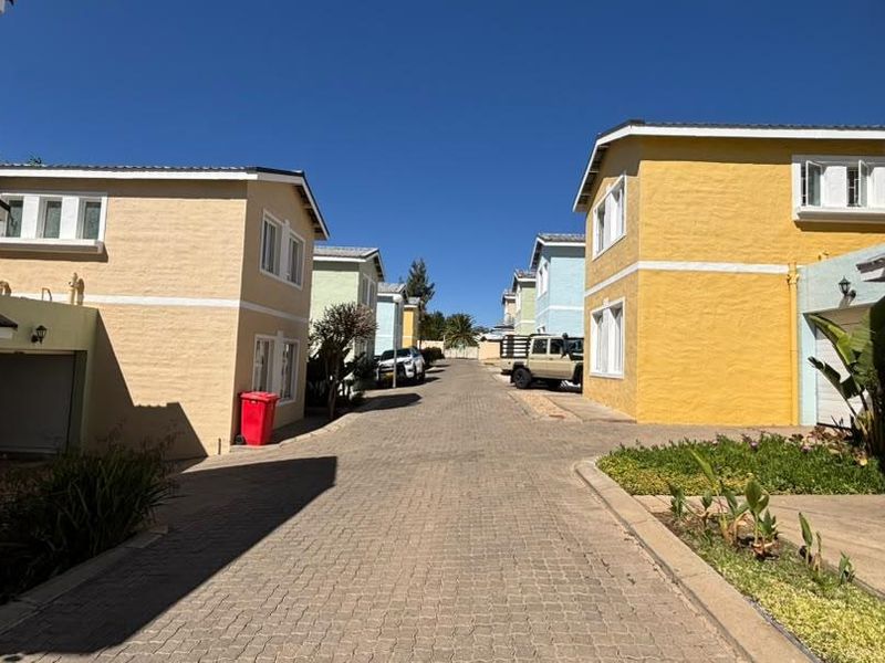A view of the townhouse complex driveway featuring paved surfaces and multiple residential units with colorful exterior facades.