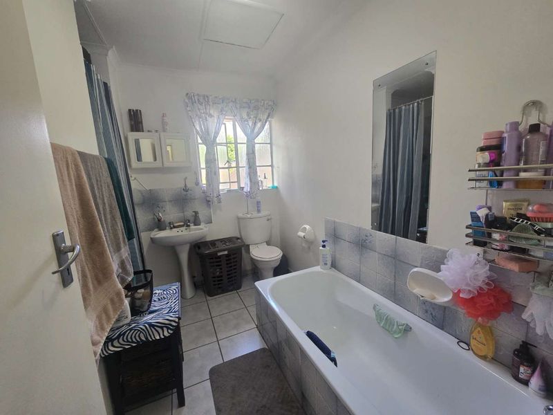 A functional bathroom featuring a pedestal basin, toilet, and bathtub with tiled splashbacks and flooring.