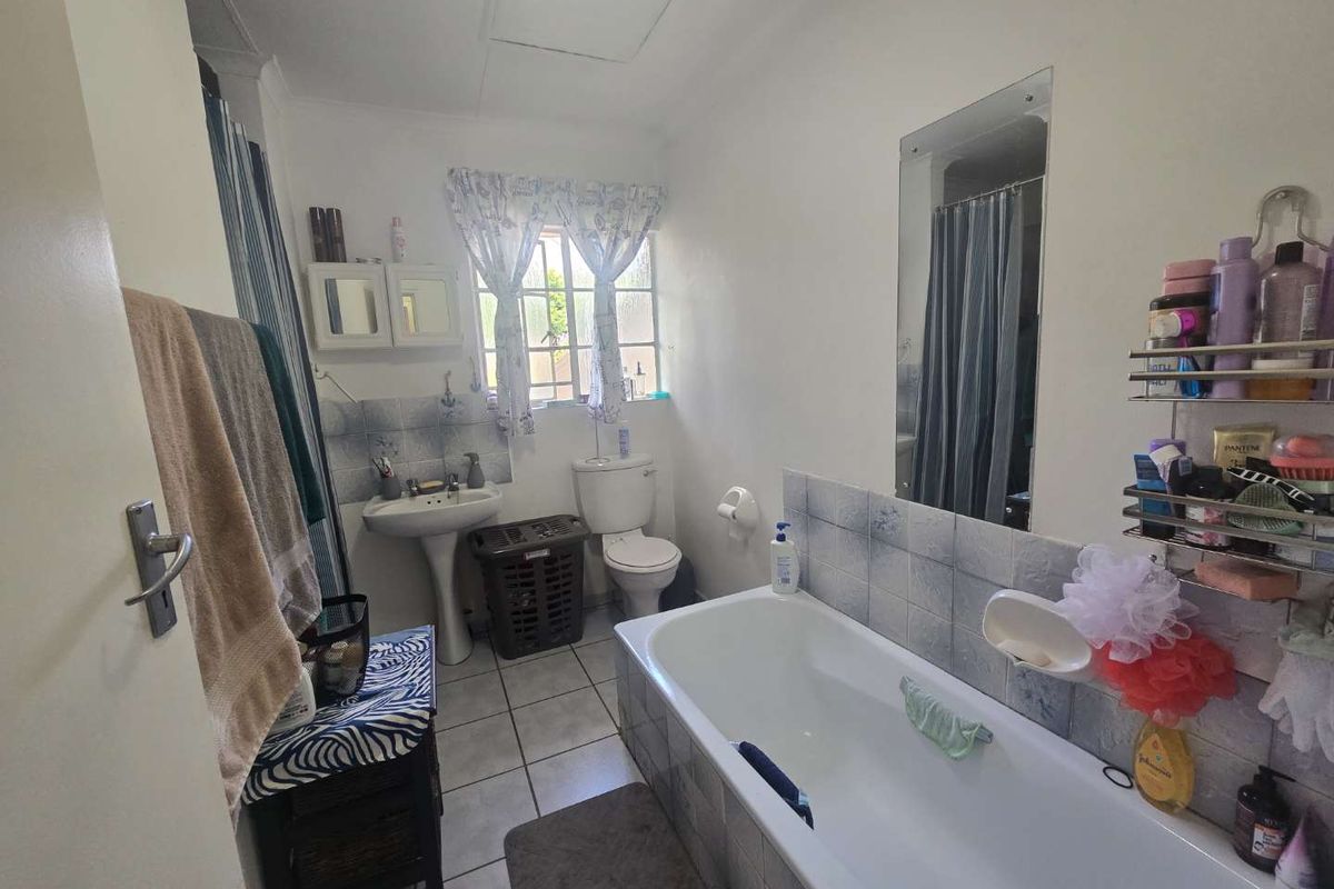 A functional bathroom featuring a pedestal basin, toilet, and bathtub with tiled splashbacks and flooring.