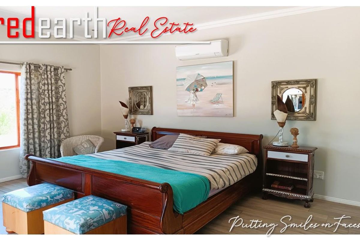 A well-maintained bedroom featuring neutral wall tones, wood-look flooring, and a wall-mounted air conditioning unit.