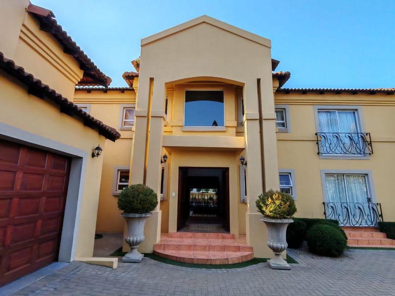 A well-maintained double-storey residential facade featuring a paved driveway, tiled entrance steps, and decorative wrought iron balcony railings.
