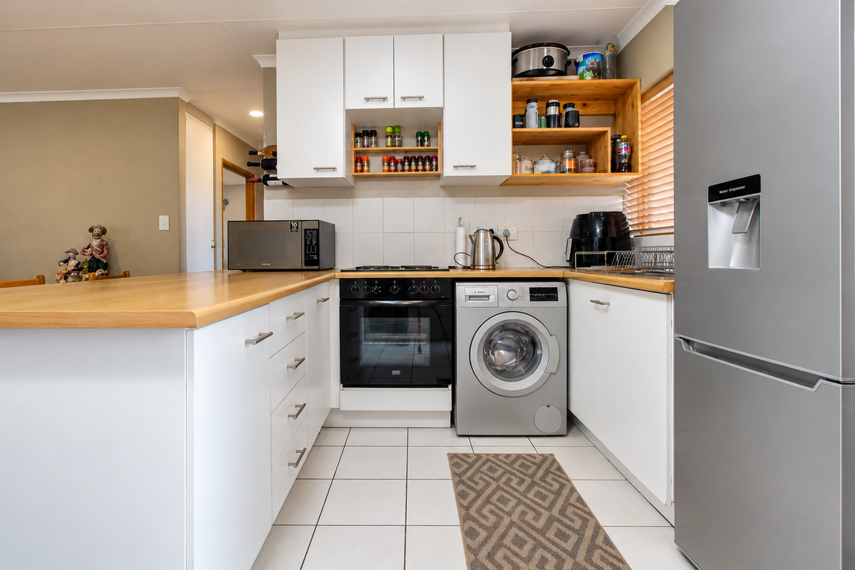 A functional kitchen featuring white cabinetry, laminate countertops, tiled backsplash, built-in oven, gas hob, and an integrated washing machine.