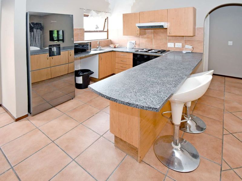 Functional kitchen featuring granite countertops, built-in cabinetry, tiled flooring, and integrated appliances with a breakfast bar layout.