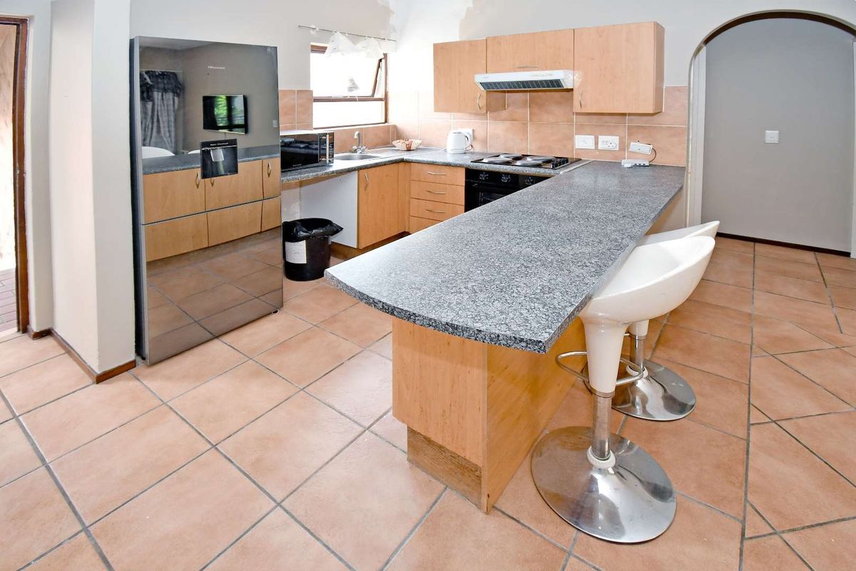 Functional kitchen featuring granite countertops, built-in cabinetry, tiled flooring, and integrated appliances with a breakfast bar layout.