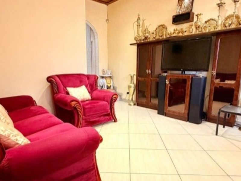 A living room featuring tiled flooring and an arched doorway, providing a functional space for relaxation.