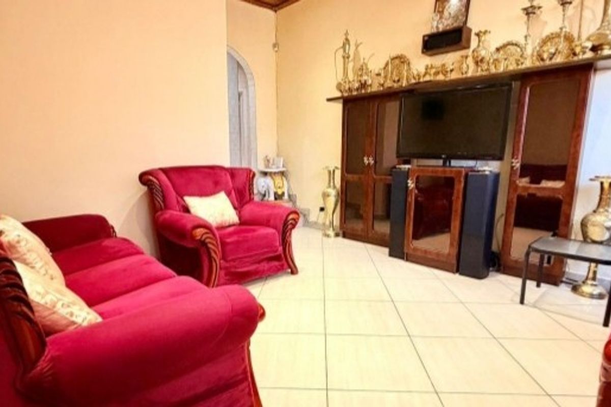 A living room featuring tiled flooring and an arched doorway, providing a functional space for relaxation.