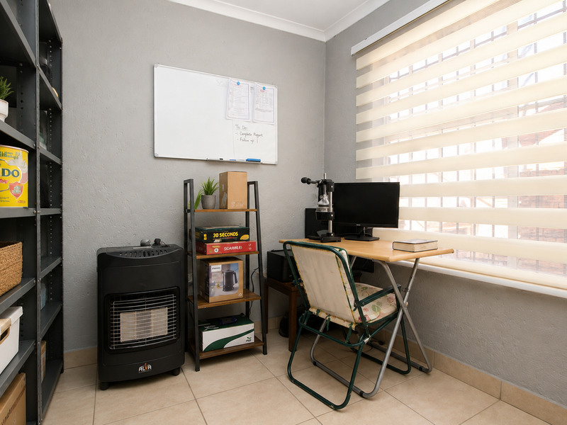 A functional home office space featuring tiled flooring and modern roller blinds, providing a practical area for work or study.