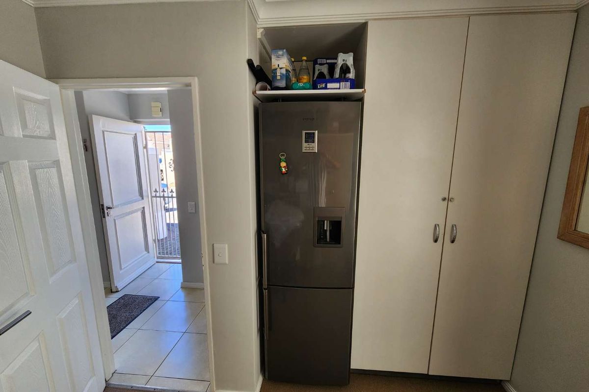 A functional kitchen area featuring built-in cabinetry and a dedicated space for a refrigerator, with an adjacent doorway leading to an exterior entrance.